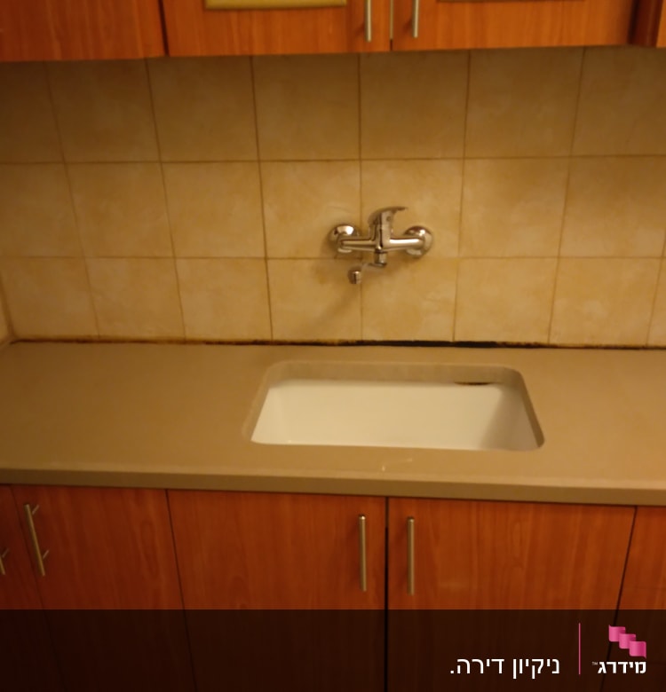 כיור מטבח עם ברז על רקע אריחים